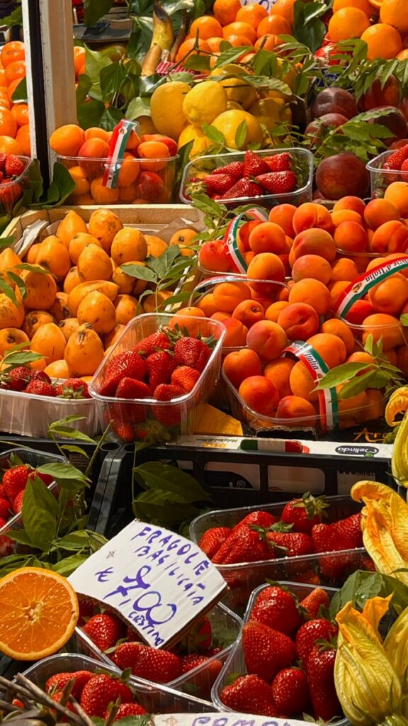 Vibrant assortment of fruits including strawberries, oranges, and apricots at a local market.