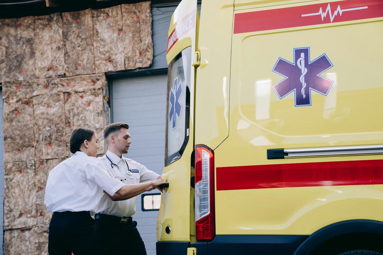 embark Two paramedics close the rear doors of an ambulance, preparing for emergency response.